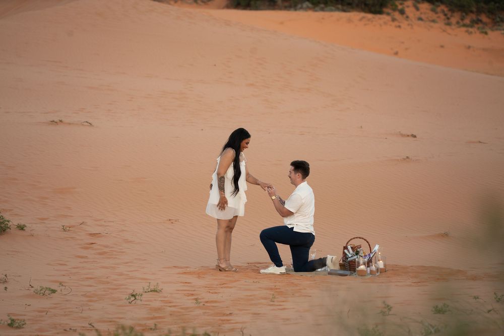 Couple embracing on red desert sand dunes in southern Utah at golden hour