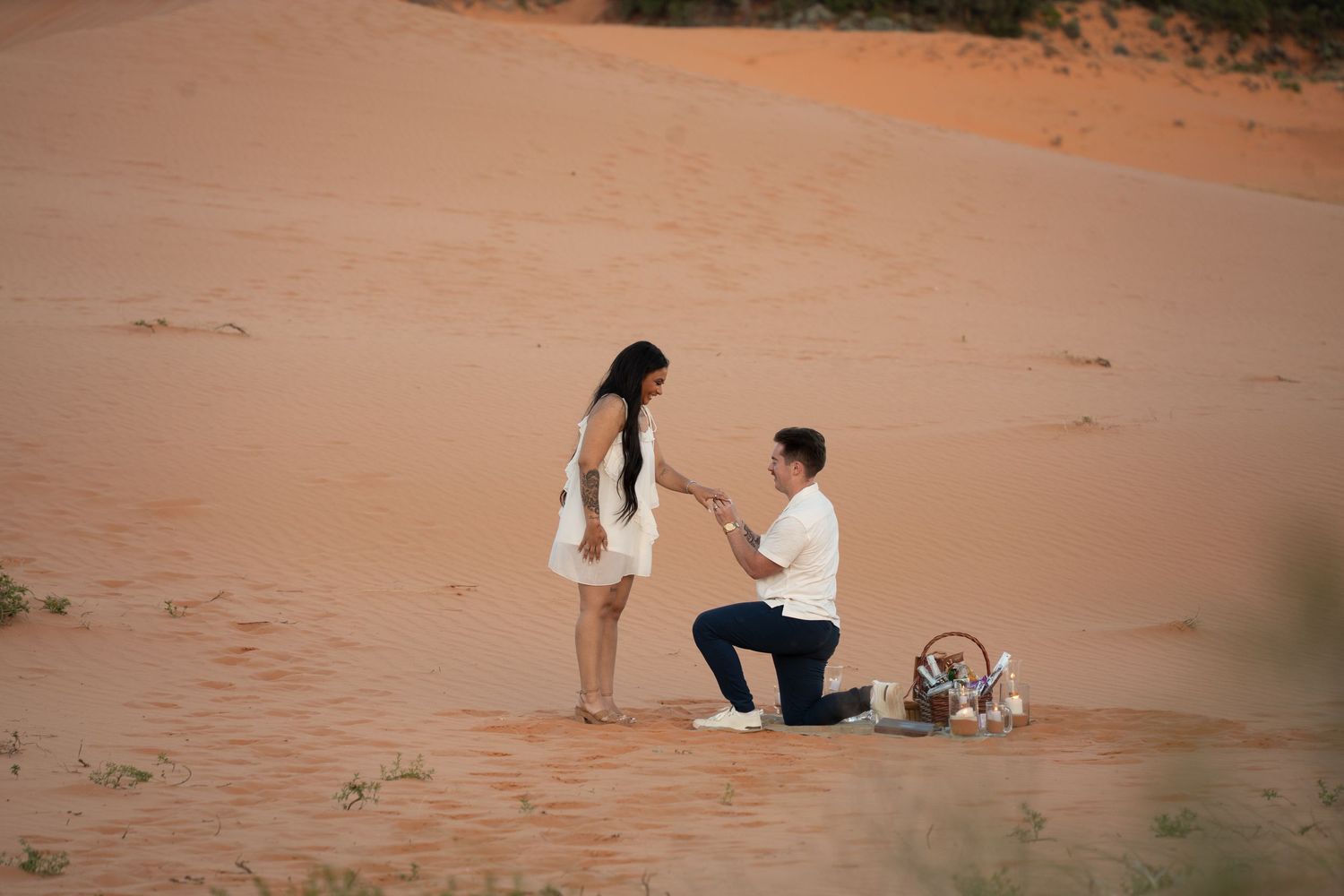 Couple celebrating an engagement on red desert sand dunes in southern Utah, a representative red-rock image, not a photo taken in St. George.
