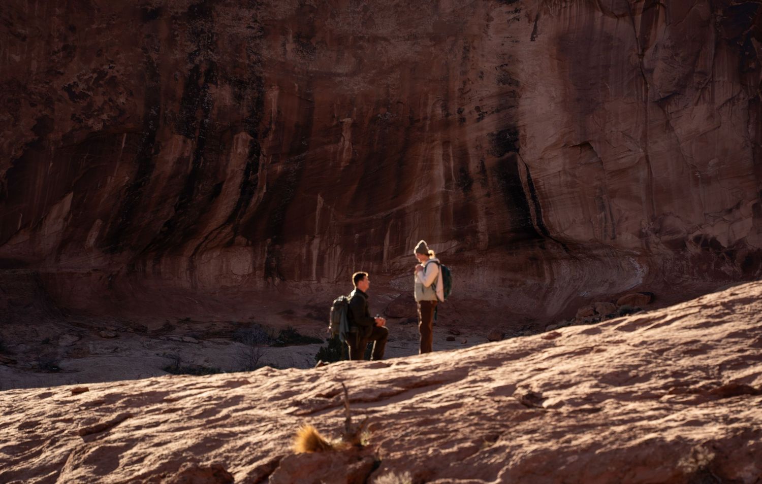 man proposes to his girlfriend beneath corona arch moab utah hiking proposal