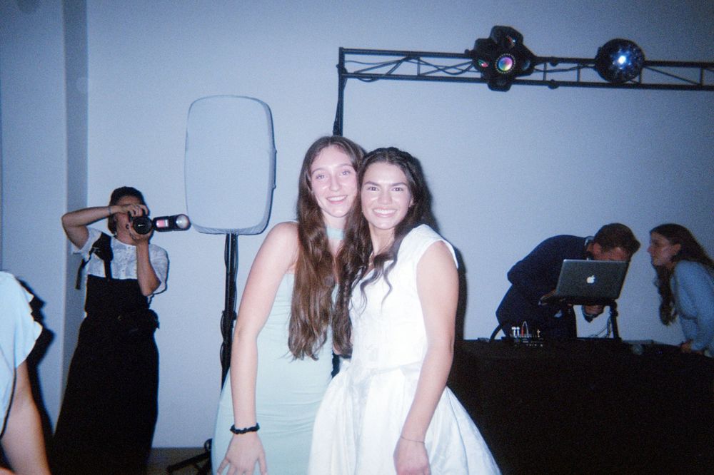 Bride and her bridesmaid smiling at the camera in a film-style photo