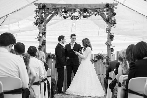 Bride and groom exchanging vows under a floral arch at their wedding ceremony