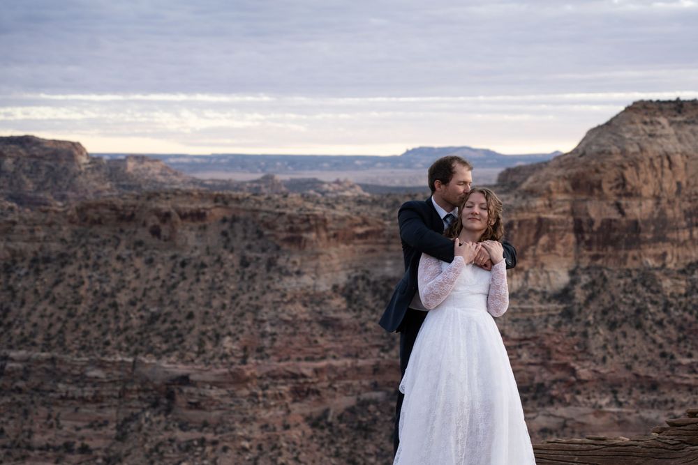 Groom kissing bride's forehead in front of Little Grand Canyon scenery