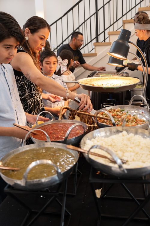 Wedding guests serving themselves from a buffet spread at the reception