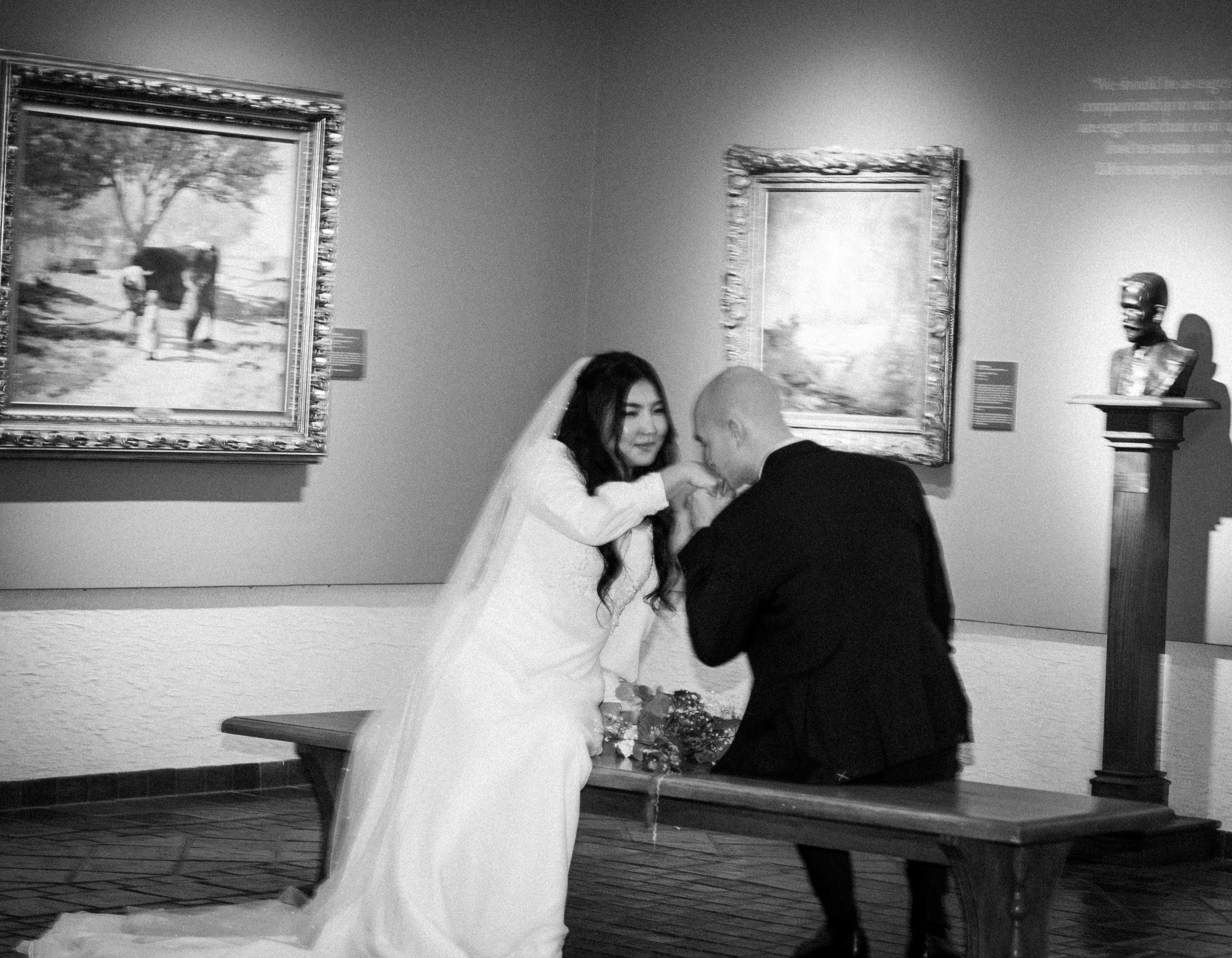 groom kisses bride's hand in quiet secret moment in the Springville Art Museum winter bridal portraits in Utah