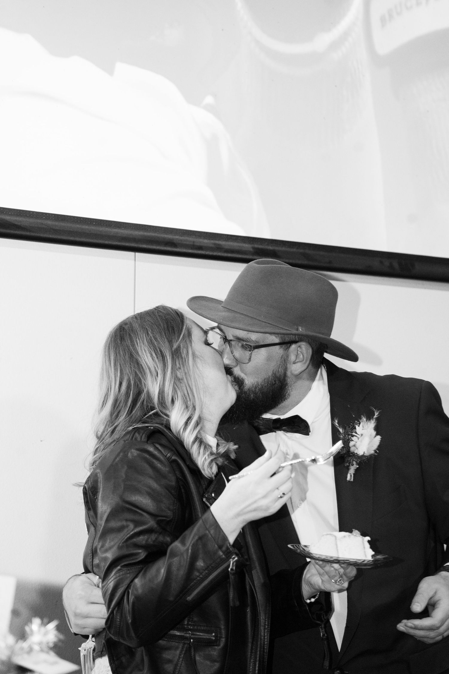 A romantic black and white photo sequence shows a couple sharing intimate moments and kisses after wedding cake cutting in Orem Utah
