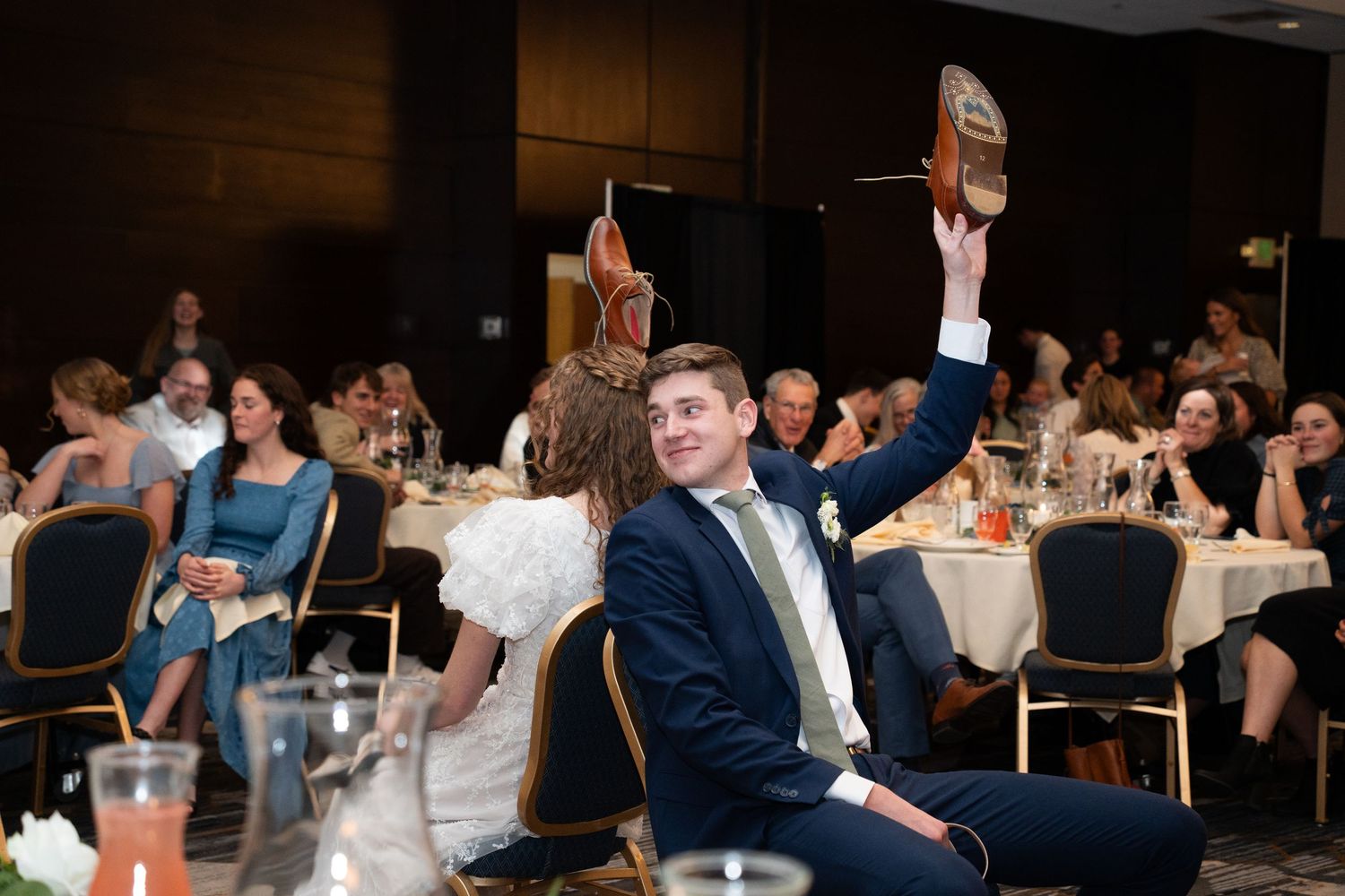 bride and groom play the shoe game at wedding reception in provo utah candid photo